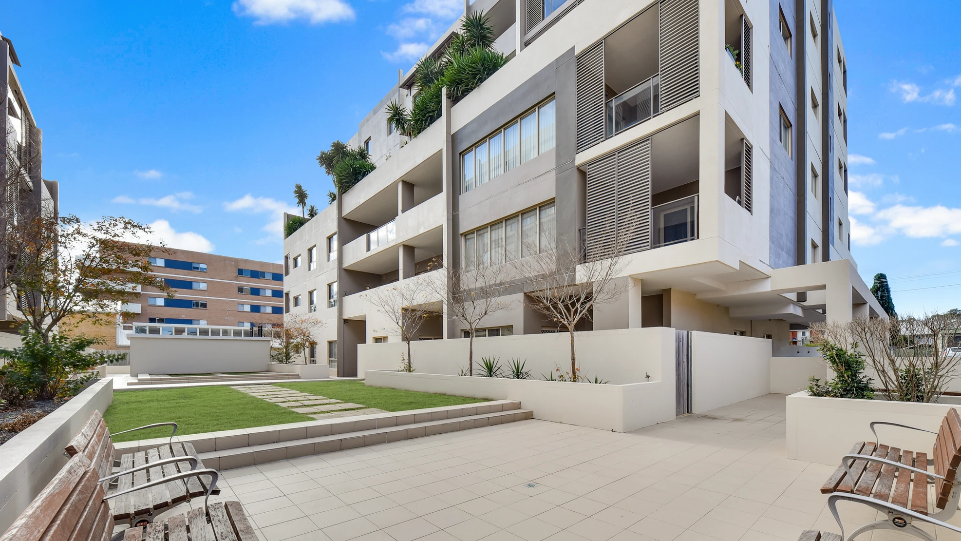 Garden courtyard with lawn, paved terrace and seating at Parkstone Place